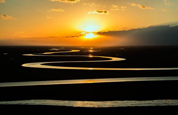 Zachodzące słońce nad rzeką rozlewającą sie po równinie-ciekawy Quiz o rzekach świata