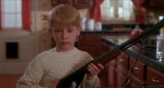 Macaulay Culkin w filmie Kevin sam w domu, trzyma strzelbę, czeka na rabusi, scena z komedii