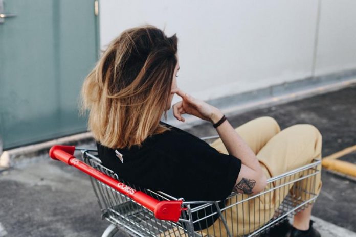 Dziewczyna siedząca w sklepowym wózku